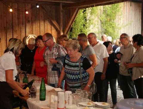 Gäste an einem Ausschanktisch unter dem Holzdach
