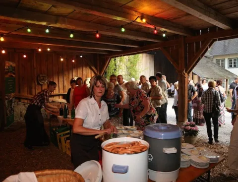 Gäste an einem Buffettisch unter dem Holzdach