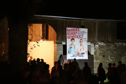 Besucher vor einem Plakat an der Scheunenwand