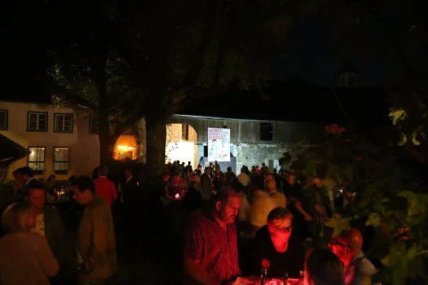 Besucher im Hof, im Hintergrund rot beleuchtete Fenster