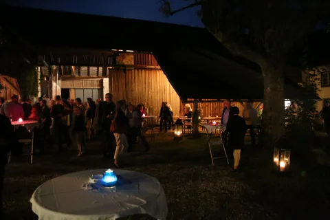 Stehtische mit Kerzen im Hof, dahinter Besucher