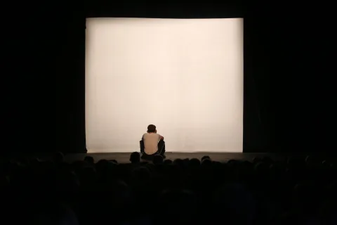 Eine Person sitzt allein vor der hellen Leinwand
