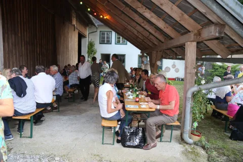 Gäste an Biertischen unter dem Holzdach