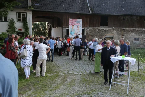 Besucher im Hof, im Hintergrund ein Plakat