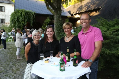 Drei Gäste an einem Stehtisch mit Flaschen