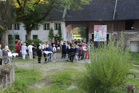Besucher im Hof vor dem Plakat