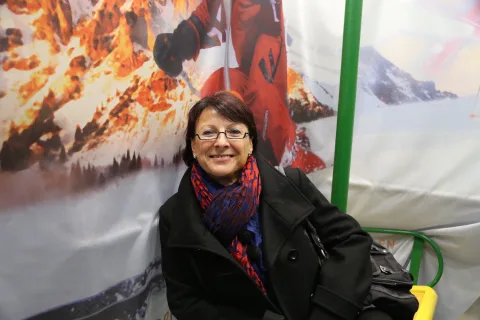 Eine Besucherin sitzt vor der Schneelandschaft des Fotopunkts.