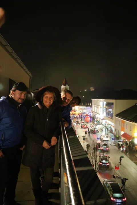 Gäste auf der Terrasse blicken hinunter auf die beleuchtete Straße.