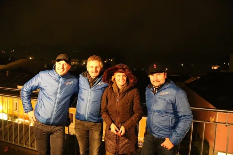 Vier Gäste in Vereinsjacken auf der Terrasse bei Nacht.