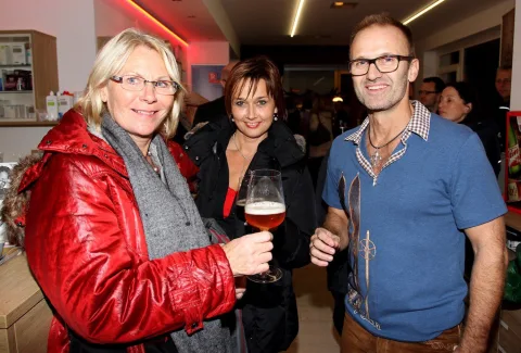 Drei Gäste mit Bier und Wein im Verkaufsraum.