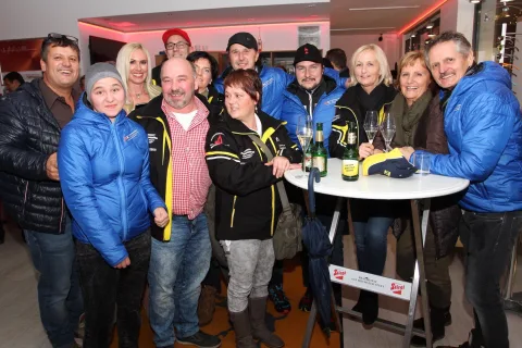 Eine große Gruppe Gäste an einem Stehtisch im Verkaufsraum.
