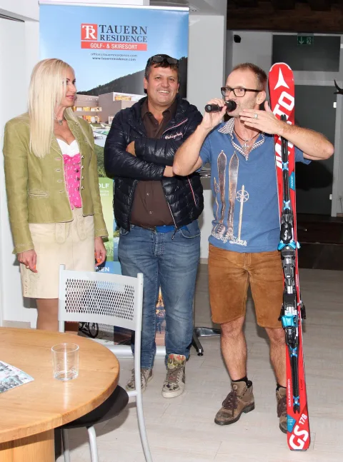 Ein Gast hält bei der Verlosung ein Paar Ski und spricht ins Mikrofon.
