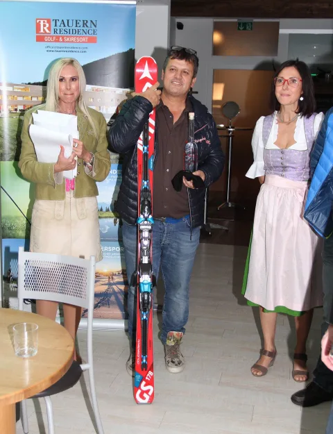 Ein Gewinner mit einem Paar Ski, daneben Hostess und Dirndlträgerin.