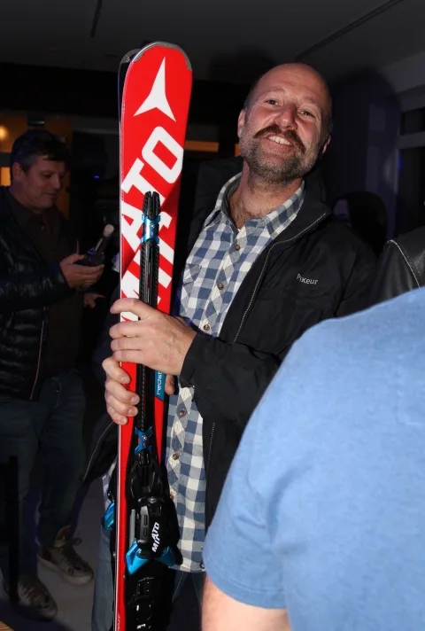 Ein Gewinner hält lachend das gewonnene Paar Ski in die Höhe.