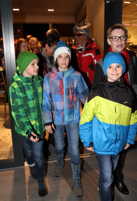 Drei Kinder in Winterjacken im Eingangsbereich.