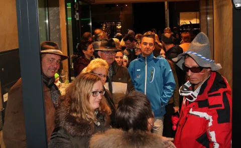 Gäste im Eingangsbereich, im Hintergrund die beleuchtete Straße.