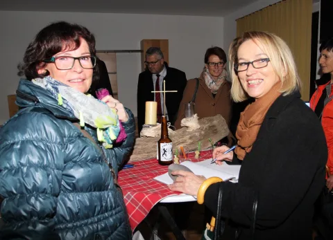 Besucherinnen tragen sich am Gewinnspieltisch ein.