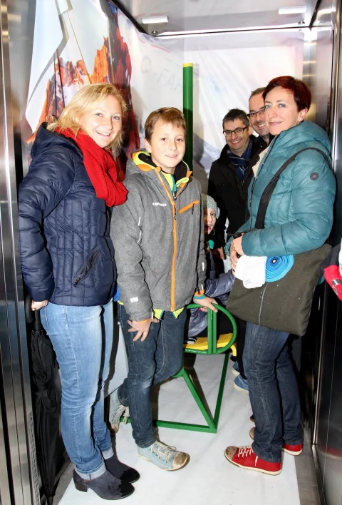 Eine Familie mit Kind am Fotopunkt im Aufzug.