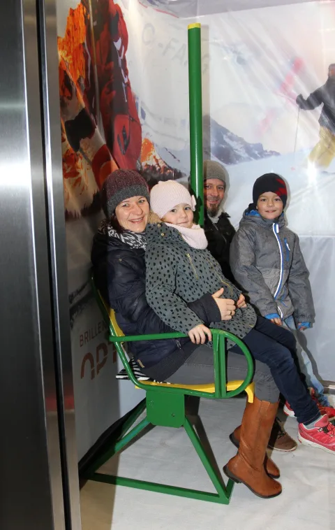 Drei Kinder sitzen im Sessellift des Fotopunkts.