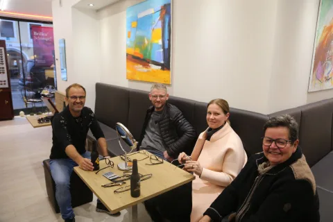 Eine Runde sitzt auf einer Bank an einem Tisch mit Bierflaschen und unterhält sich