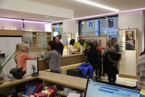 Besucher im Verkaufsraum zwischen Brillenregalen und Beratungsplätzen