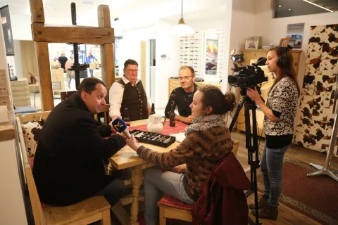 Ein Kamerateam filmt eine Beratung an einem Tisch im Geschäft