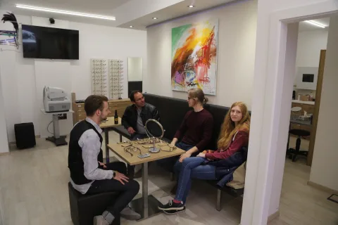 Drei Personen sitzen an einem Tisch im Verkaufsraum und unterhalten sich