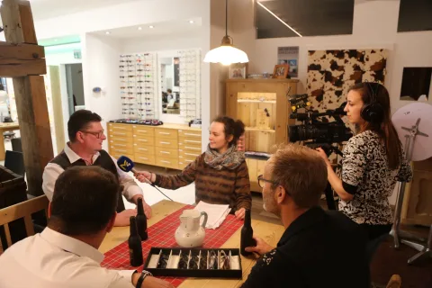 Eine Beratung an einem Tisch im Geschäft, vier Personen sitzen um einen Brillenkoffer