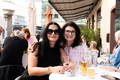 Zwei Frauen mit Sonnenbrillen an einem gedeckten Tisch im Gastgarten