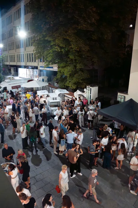 Blick von oben auf eine abendlich gefüllte Straße mit Zelten und vielen Menschen