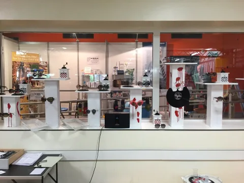 Der Messestand von außen, mit weißen Präsentationstischen und Brillen hinter Glas