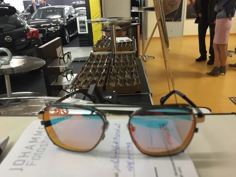 Eine Sonnenbrille mit Holzbügeln liegt auf einem Prospekt
