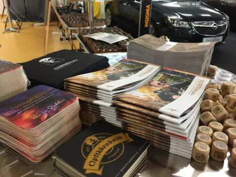 Stapel von Prospekten und T-Shirts auf einem Tisch am Messestand