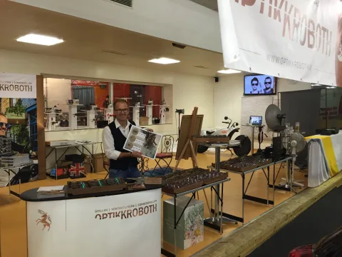 Ein Mitarbeiter am Messestand, im Hintergrund das Banner mit dem Firmennamen