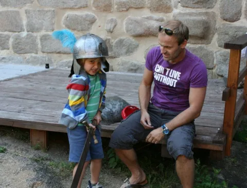 Ein Kind mit Helm und ein Mann auf einer Holzbank