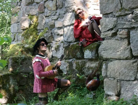 Ein Darsteller in rosa Wams auf einer bewachsenen Mauer