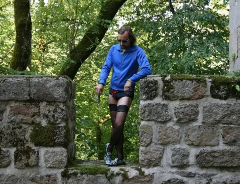 Ein Mann im blauen Gewand auf einer Mauer im Wald