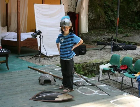 Ein Kind mit Helm neben Aufnahmetechnik und weißem Hintergrundtuch