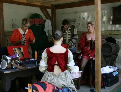 Garderobe mit Kostümen, zwei Darstellerinnen beim Umziehen