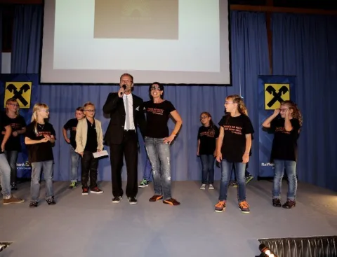 Eine Gruppe Kinder mit zwei Erwachsenen auf der Bühne