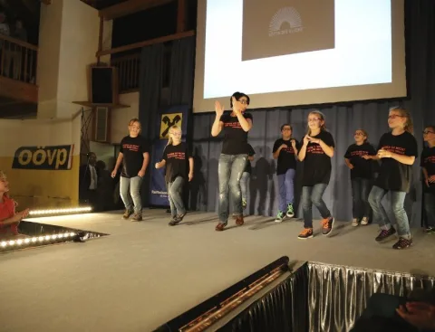 Kinder tanzen auf der Bühne, davor das Publikum