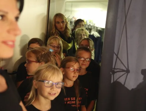 Kinder mit Brillen warten hinter der Bühne