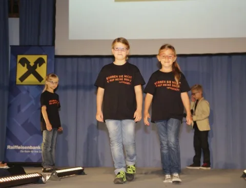 Drei Kinder auf dem Laufsteg vor blauem Vorhang
