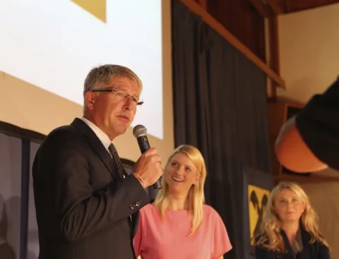 Ein Mann mit Mikrofon und zwei Frauen auf der Bühne
