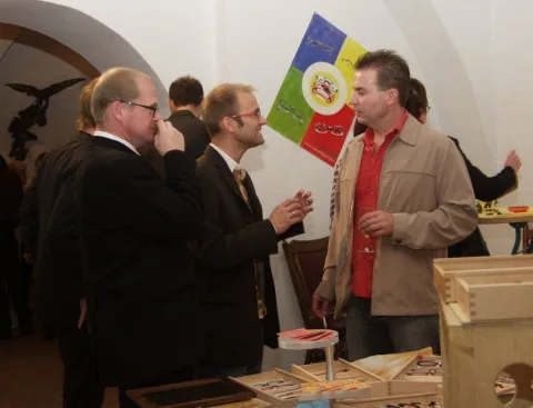 Gäste unterhalten sich in einem Raum mit Holzdachstuhl, im Hintergrund ein Werbebanner
