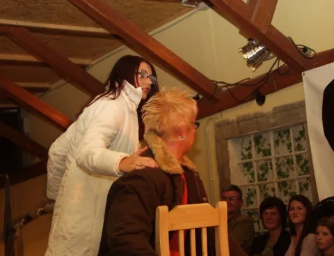 Eine Frau im weißen Mantel beugt sich zu einer sitzenden Besucherin hinunter