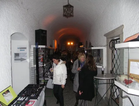 Besucher an einer Ablage mit Brillen, dahinter der helle Gewölbegang