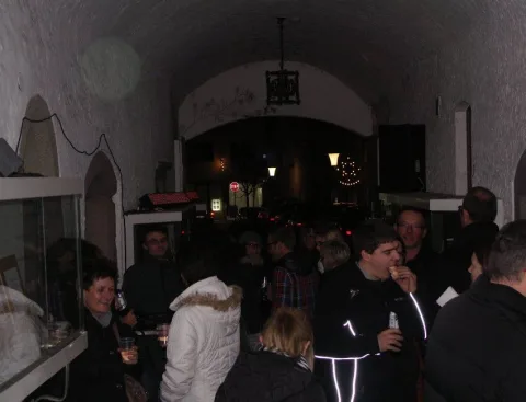Blick in den Gewölbegang mit Gästen und Lampen an der Decke