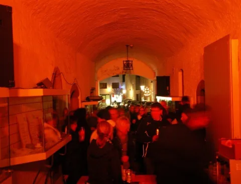 Der Gewölbegang in orangerotes Licht getaucht, im Hintergrund die Bar