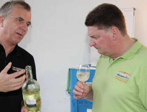 Zwei Männer mit Weinflasche und Glas im Gespräch